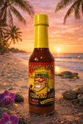 Tahiti Joe's Volcano Ahh hot sauce bottle on a beach with sunset and palm trees in the background
